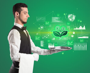 Handsome young waiter in tuxedo holding currency icons on tray