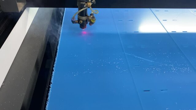 Cutting transparent plexiglass on a laser machine. Cutting plastic with a red laser. CNC machine for the manufacture of blanks.Burning through the material.
