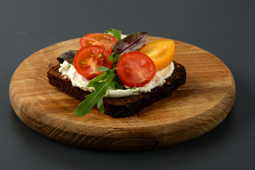 Bruschetta with tomato, arugula and soft cheese on wooden tray