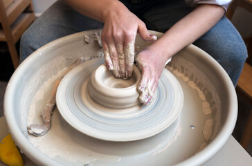 A potter works on a fast spinning potter's wheel and makes a bowl. Creating ceramics.