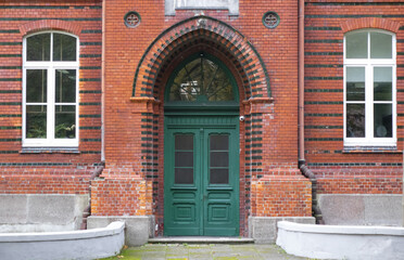 Fototapeta na wymiar Old green door on a brick wall building with windows