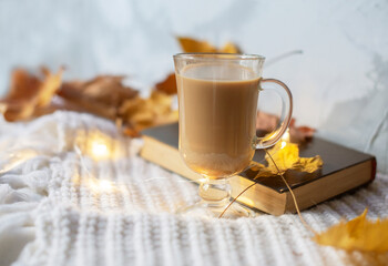 Autumn flat lay composition. Warm comfort white sweater, book, coffee cup, dried yellow leaves....