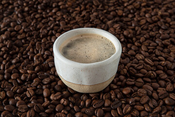 A mug with coffee on a pile of coffee beans