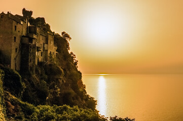 France. Corsica. Cap Corse. The old houses of the village clinging to the cliff at sunset