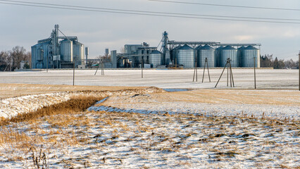 Silver silos against the blue sky in winter. Grain storage in winter at low temperatures....