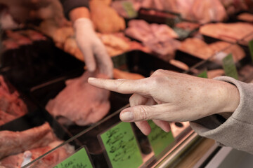 Fototapeta na wymiar A woman points to an item in a butcher's shop that she wants to buy. Shopping market, Austria, Salzburg