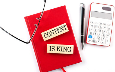 CONTENT IS KING text on wooden block on red notebook