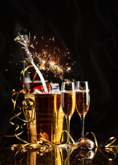 Golden Bucket with champagne, two glasses and a golden serpentine on a black background