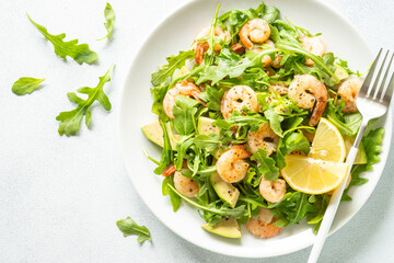 Shrimp salad with arugula and avocado at white. Close up.