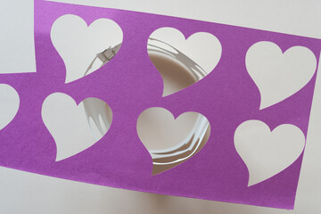 close up of violet paper stencil with heart shape cutouts