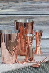 Stylish and trendy bar accessories. Jag, muddler, squeezer, shaker, strainer, jigger - accessories for bartenders in restaurants and bars. Bronze and copper cocktail bartender set