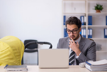 Young male employee looking after new born at workplace