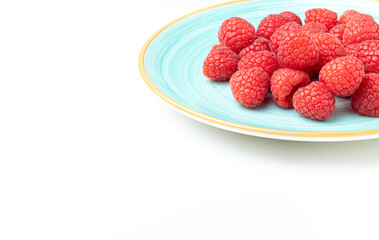 sky blue plate full of raspberries on white background