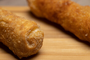 closeup photo of some guacamole sauce and two breaded cheese rolls or tequeños