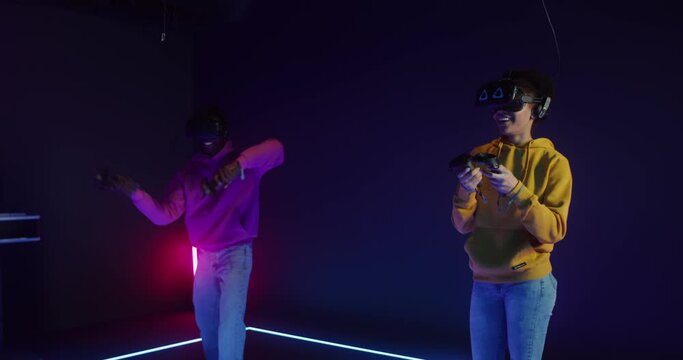 A man and woman are playing online game in virtual reality headsets using joysticks