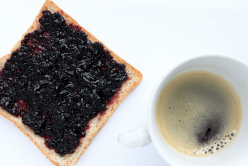 Bread with sweet blackberry jam and a cup of espresso coffee on white background.top view 
