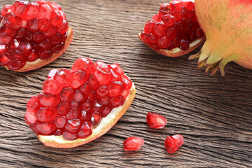 Fresh red pomegranate fruit with seeds on rustic wooden table. Top view.