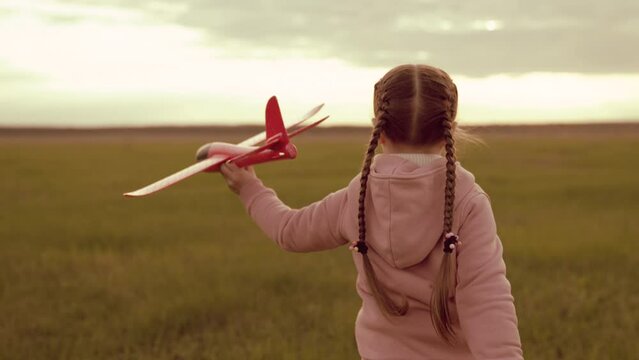 little girl runs sunset with toy plane her hand. kid child run around green field sunset playing toy plane. childhood dream becoming pilot. little superhero child. children run park. happy girl pilot