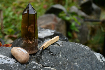 A tall smoky quartz healing crystal with reiki symbol and smudge sticks.