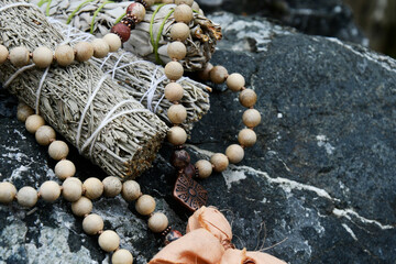 An image of healing smudge sticks with a mala prayer necklace made with wooden beads. 