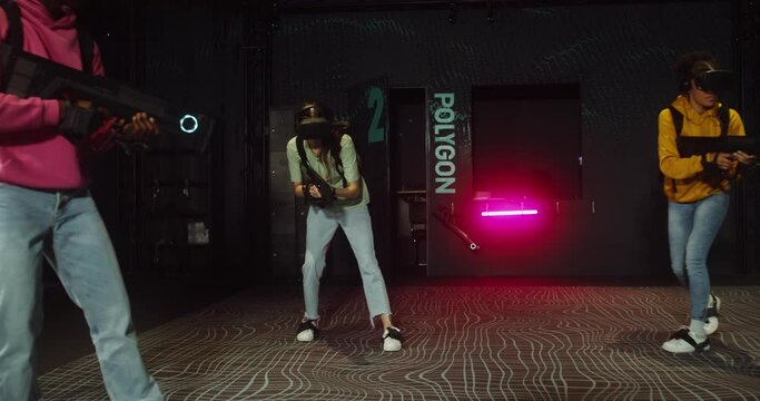 A group of friends in virtual reality headsets play online video game with gun controllers