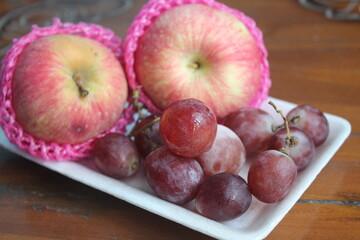 apples and red grapes on a white plate
