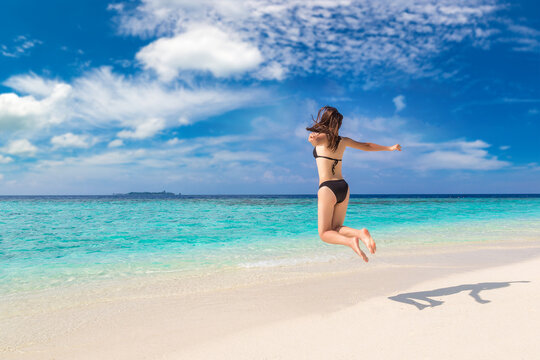 Woman in bikini jumping at beach