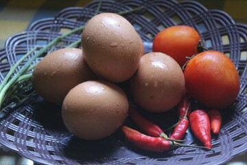 a few eggs, tomatoes and chilies on a plate