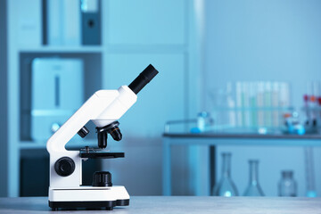 Modern medical microscope on gray table in laboratory, space for text