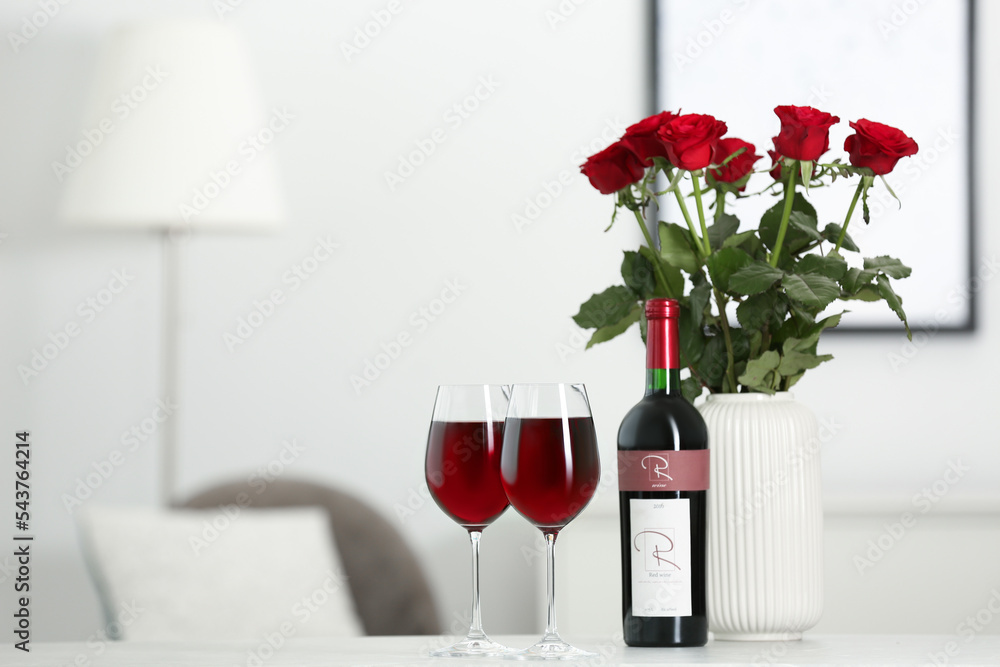 Canvas Prints Bottle, glasses of red wine and vase with roses on table in room, space for text. Romantic date