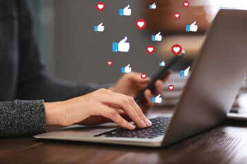 Young woman using laptop and smartphone indoors, closeup. Social media