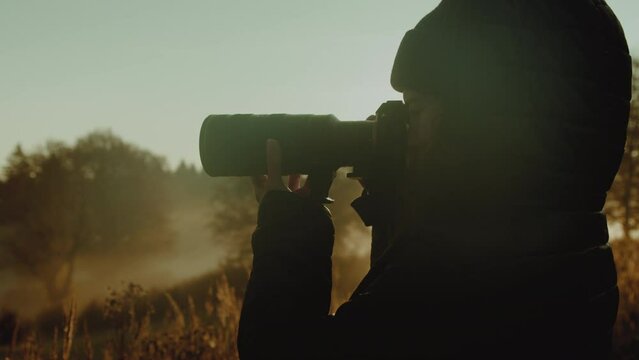 Woman Takes Photo Through Telephoto Lens During a Cold Autumn Sunrise or Sunset in Nature