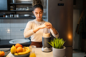 one woman young adult caucasian female preparing healthy breakfast in the kitchen using blender to make fruit smoothie at home real people copy space healthy eating vegan and vegetarian concept