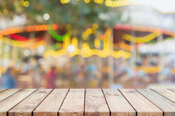 Empty wood table top and blurred carousel in amusement park in the festival of happiness background - can used for display or montage your products.