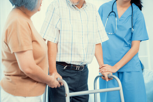 Contented Senior Man Was Helped On Folding Walking By His Wife And Caregiver. Recuperation For Elderly, Seniors Care, Nursing Home.