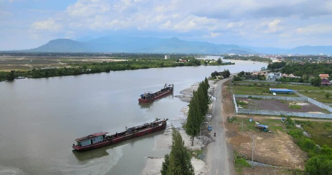 aerial drone shot of two dredging ships moored along the riverbank