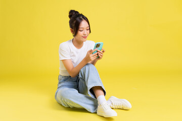 portrait of a beautiful young asian girl sitting on a yellow background