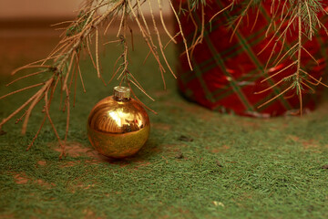 A golden Christmas ball on a dry branch of a Christmas tree without needles. Protection of forests from deforestation - concept