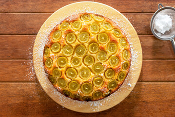 Homemade olive oil cake, topped with green grapes on wooden table background.
