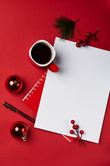 christmas decorations and a cup of coffee on a red background with a blank paper for your own message or text