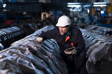 Senior male engineer worker working checking or maintaining machinery, mechanical machine at the industry factory. Male technician wear safety helmet, gloves and uniform working in the factory