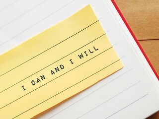 Notebook with stick note written I CAN and I WILL, concept of willpower - strong determination that...