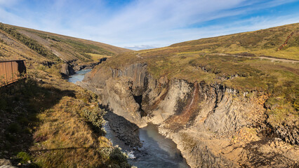 Overview of Studlagil ravine in Jokuldalur Iceland, known for its columnar basalt rock formations and the blue-green water that runs through it. It became an unexpected tourist sensation
