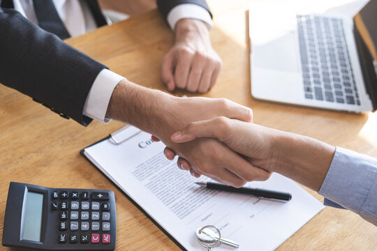 Close up hand of asian young male new landlord, tenant or rental handshake with home, apartment agent or realtor man after bank approved mortgage, loan signed purchase contract. Property of financial.