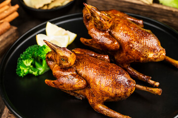 Traditional Cantonese roast pigeon on a and white porcelain plate