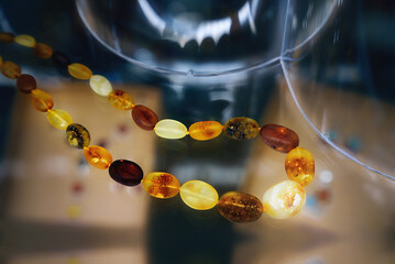 Amber beads on  a glass shelf.