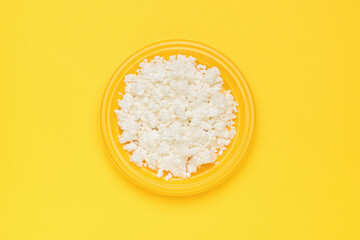 A bright yellow plate with fresh yogurt on a yellow background. Flat lay.