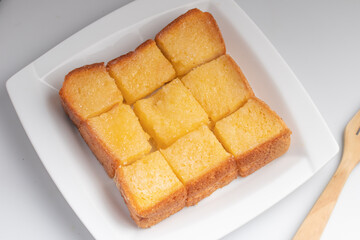 Toasted bread slices topped with sweetened condensed milk in a white plate.