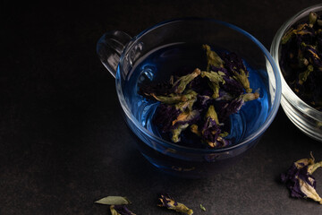 Butterfly pea flower tea in a clear glass on a black background.