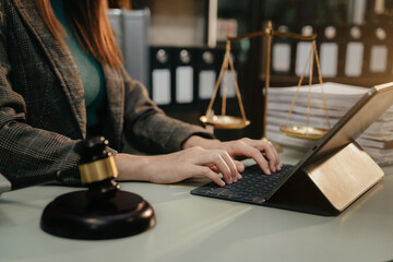 Justice and law concept. Female judge in a courtroom with the gavel working with digital tablet computer docking keyboard.